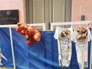 A protes sign at the Russsian embassy in Tallinn: A Teddy bear covered in "blood" and children’s clothes with written city names like “Chernihiv, Mariupol, Volnovakha, Sumy, Bucha…”.