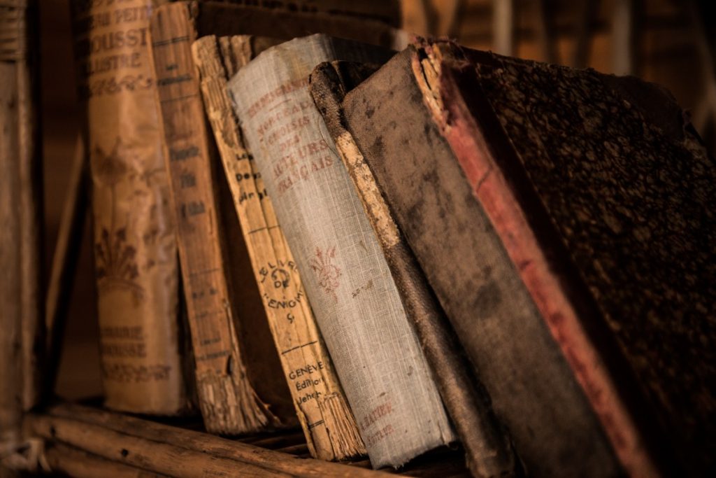Vanhoja, osin rikkinäisiä, kirjoja hyllyssä rivissä