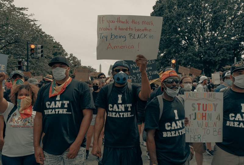 Protestors wearing face masks wear shirts that read "I can't breathe".