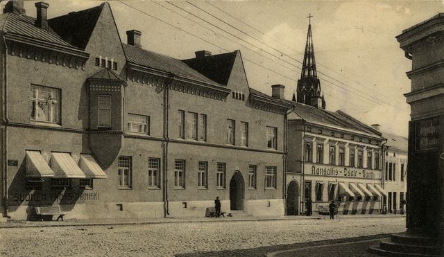 En svart-vit gatubild av Björneborg. I vänster finns en bankbyggnad med två våningar.