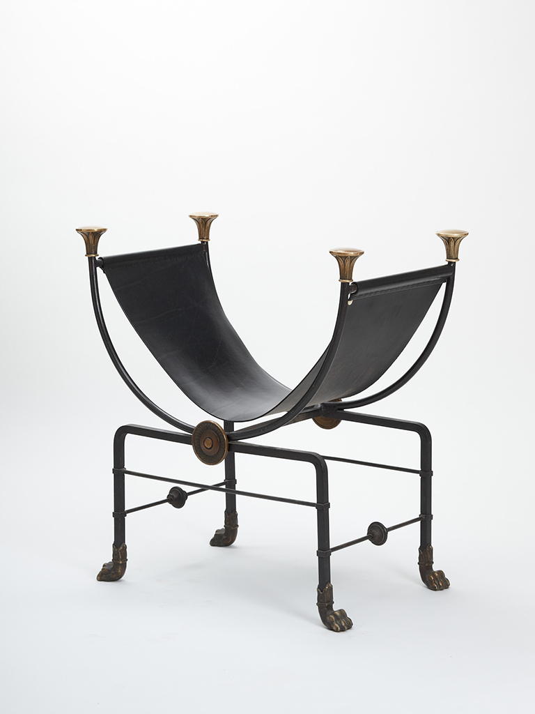 Fotografi på en stol som har formen av bokstaven U. Sitsdelen är tillverkad i svart läder och konstruktionen i smidesjärn.