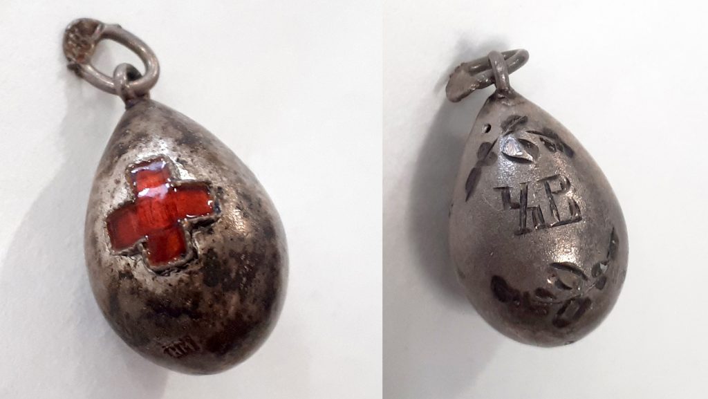 A small egg-shaped pendant decorated with the Red Cross emblem and the Cyrillic characters XB.