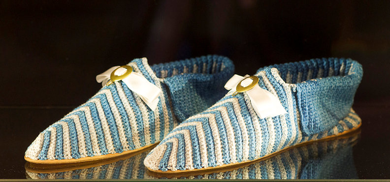 An elegant pair of blue-and-white striped footwear decorated with brass buckles and silk bows.