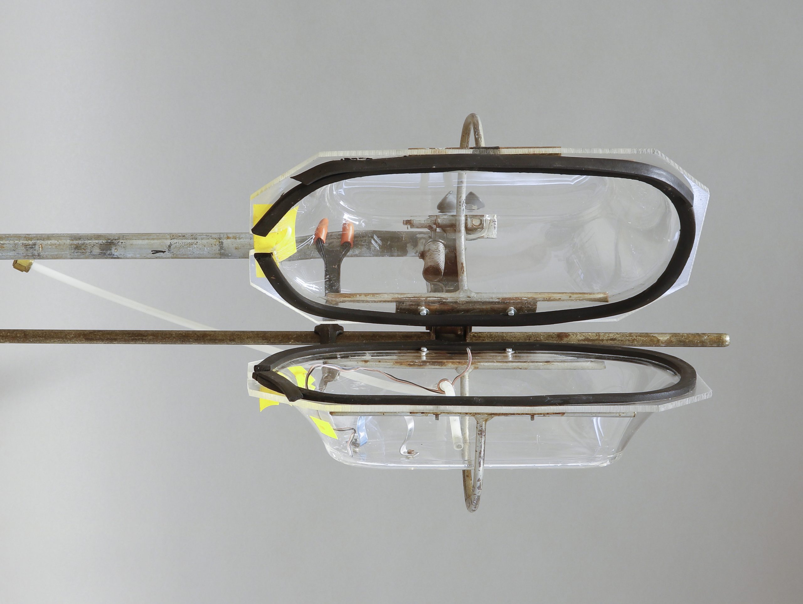 A plastic transparent research container, composed of two parts, fixed on an iron stand.