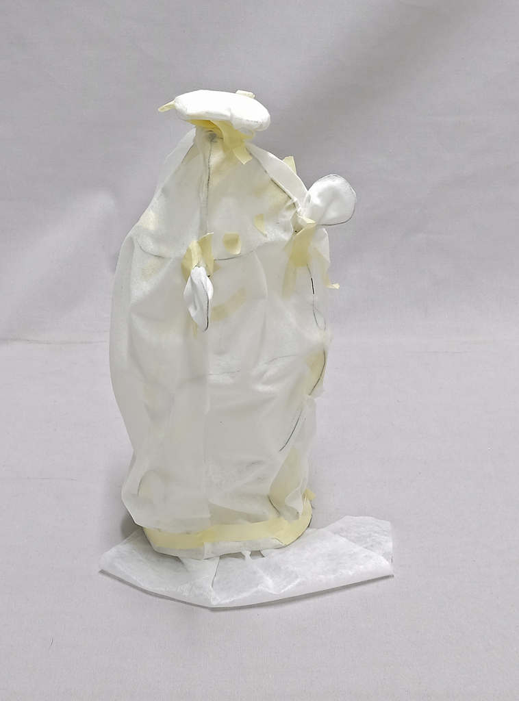 A standing soft toy assembled from white gauze, wire and masking tape, with an oblong body and ears at the top.