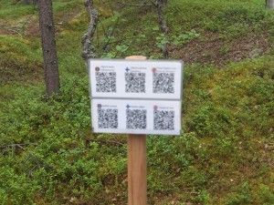 Sign with app for Second World War information at the outdoors section of Siida. Photo: Suzie Thomas, August 2015.