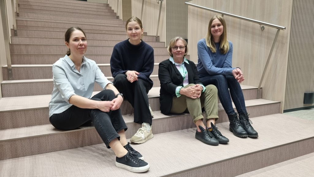 Anne Rahikka, Saara Hannula, Ellinoora Ekman och Vilma Turunen sitter på trappan i föreläsningssalen.