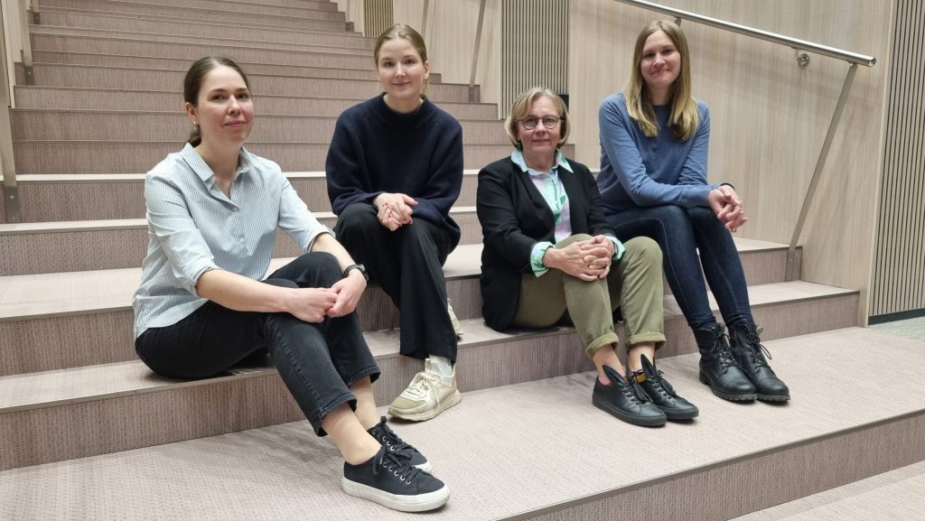 Anne Rahikka, Saara Hannula, Vilma Turunen ja Ellinoora Ekman istuvat luentosalin portailla.