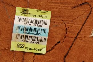 A barcode identification sheet of the Papua New Guinea Forest Authority and SGS stapled onto the end of a cut out log.