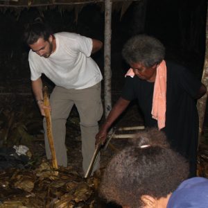 Photo of Rodolfo taking food from an earth oven in the Solomon Islands.